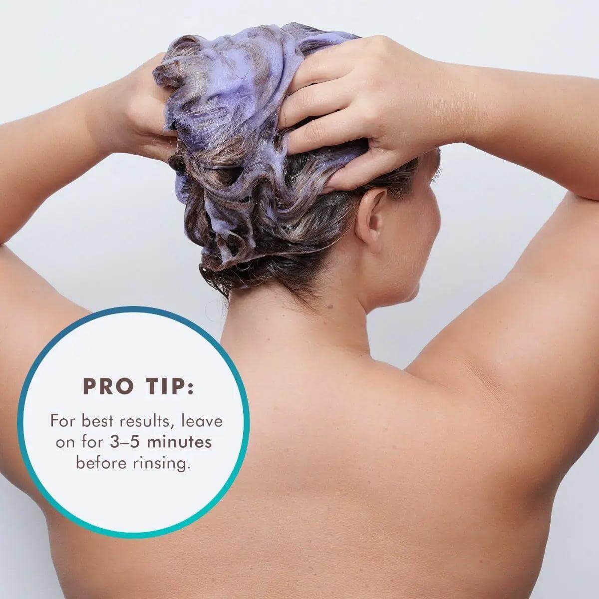 Person applying Moroccanoil Blonde Perfecting Purple Shampoo with pro tip to leave on for 3–5 minutes before rinsing.