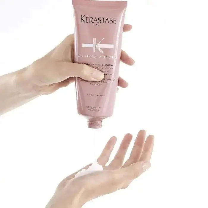 Person squeezing Kerastase Chroma Absolu Fondant Cica Chroma conditioner into hand for color-treated hair care.