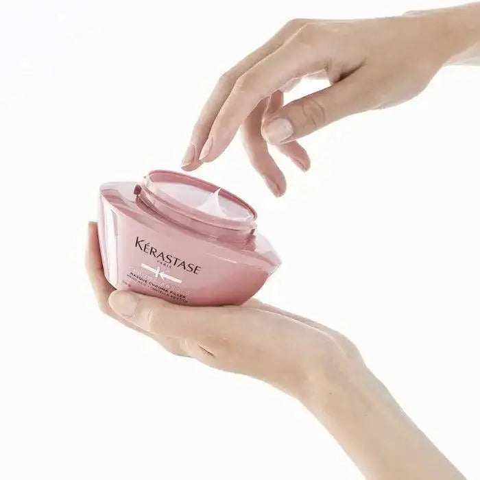 Person holding Kérastase Chroma Absolu Masque Chroma Filler hair mask designed for color-treated hair care and nourishment.