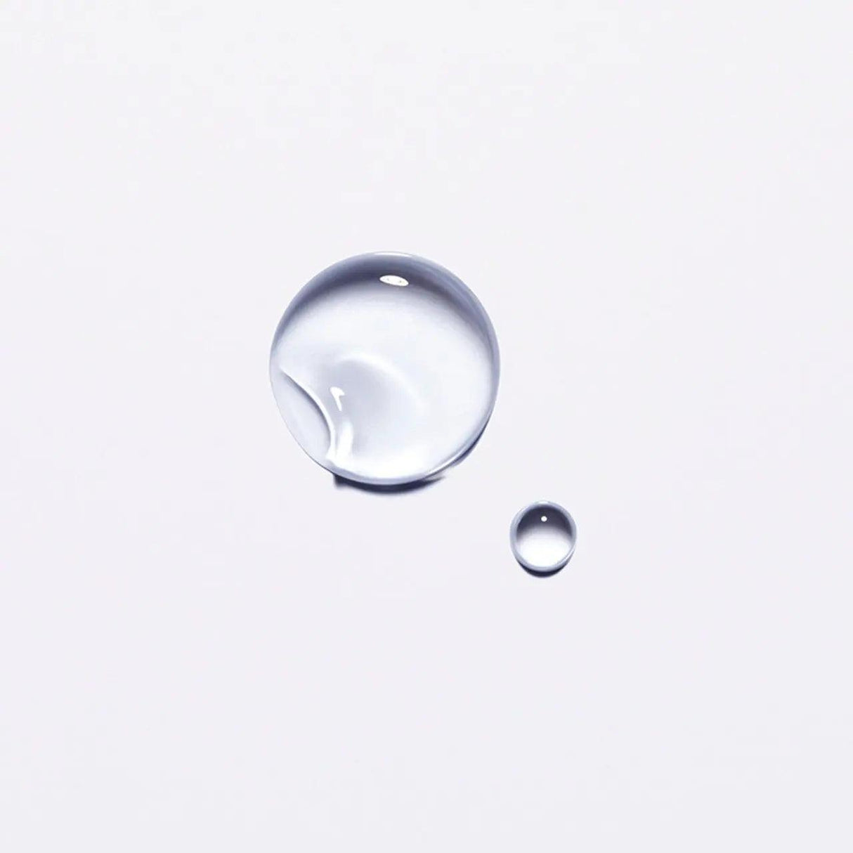 Clear drops of Kérastase Chronologiste hair oil on a white background, showcasing its lightweight, nourishing formula.