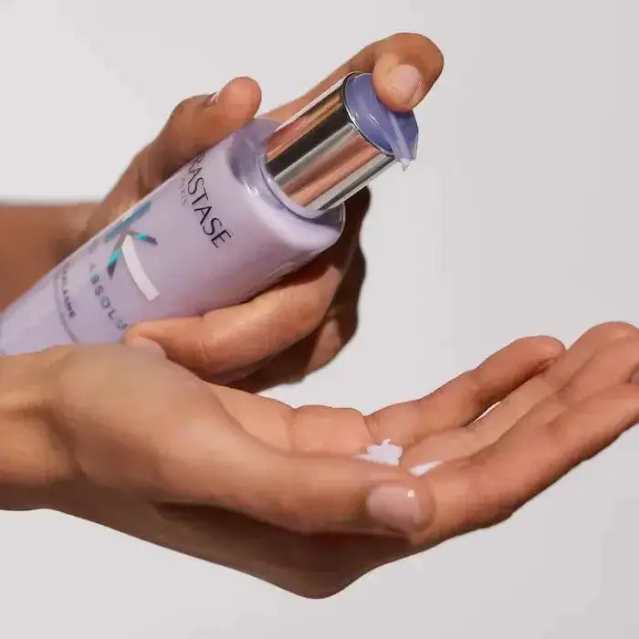 Person applying Kérastase Cicaplasme leave-in hair serum for damaged hair care into their hand.