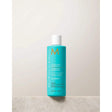 Moroccanoil Clarifying Shampoo bottle on a marble surface, enriched with Argan and avocado oils for cleansing and a shiny finish.