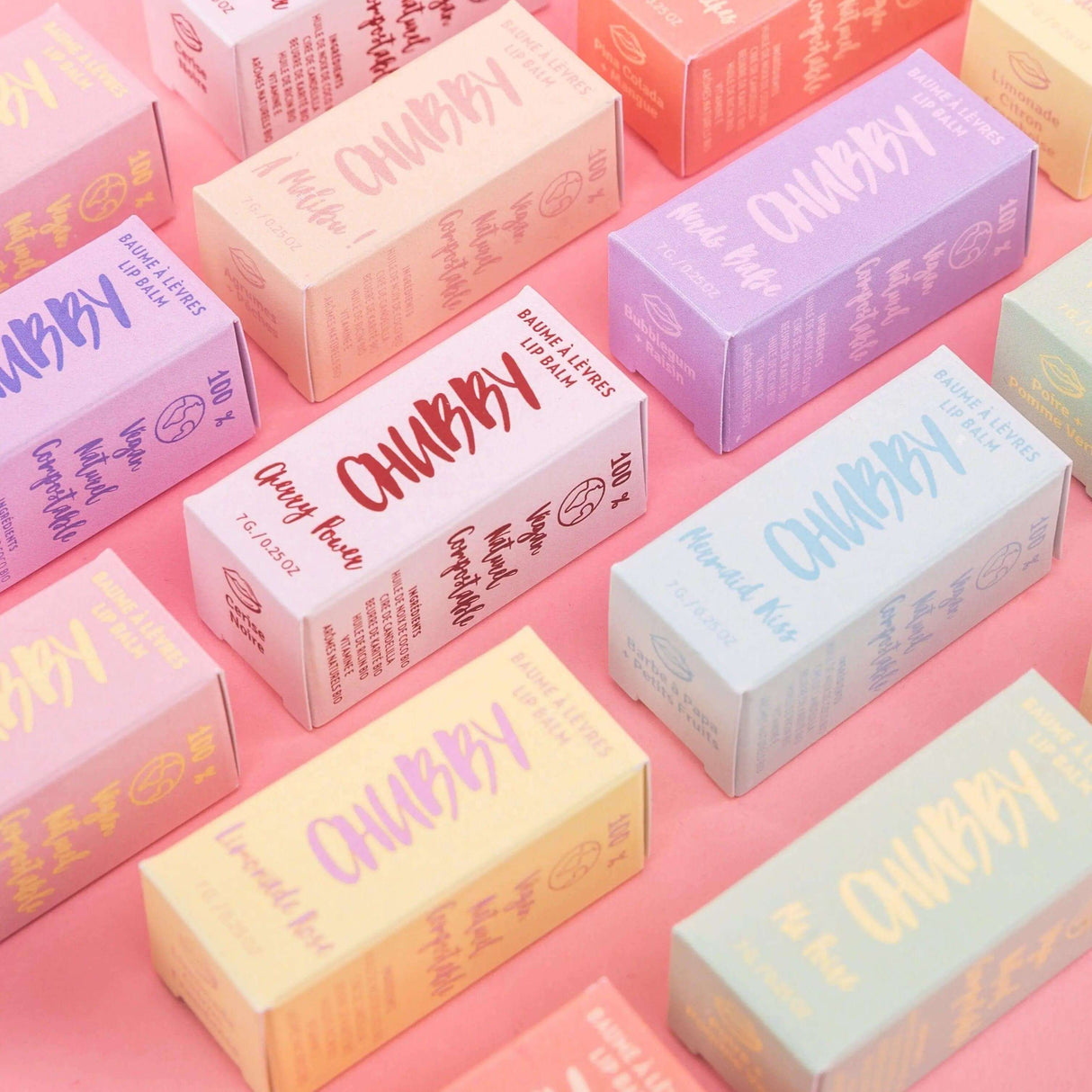 Colorful packaging of vegan, compostable lip balm with various scents, eco-friendly and handmade for smooth, hydrated lips.