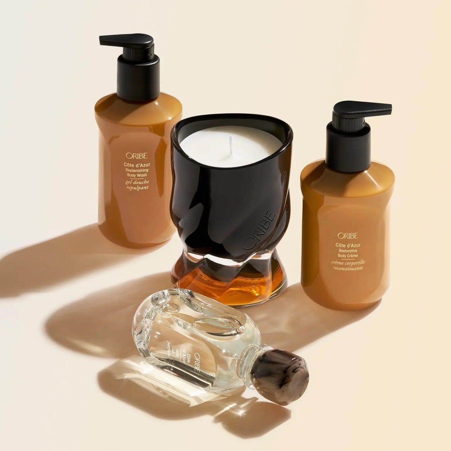 Oribe Côte d'Azur Restorative Body Crème and candle set showcasing luxury body care products with elegant design.
