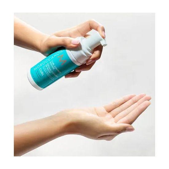 Applying Moroccanoil Curl Control Mousse for curly hair care, combating frizz and sealing moisture with argan oil.