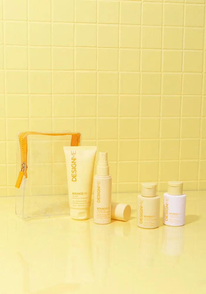 Curl Discovery Kit featuring shampoo, conditioner, curl balm, and spray gel on a yellow surface with a clear pouch.