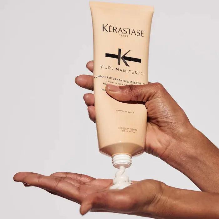 Close-up of Kérastase Curl Manifesto Fondant Hydration Essentielle being dispensed into hand, ideal for curly and wavy hair.