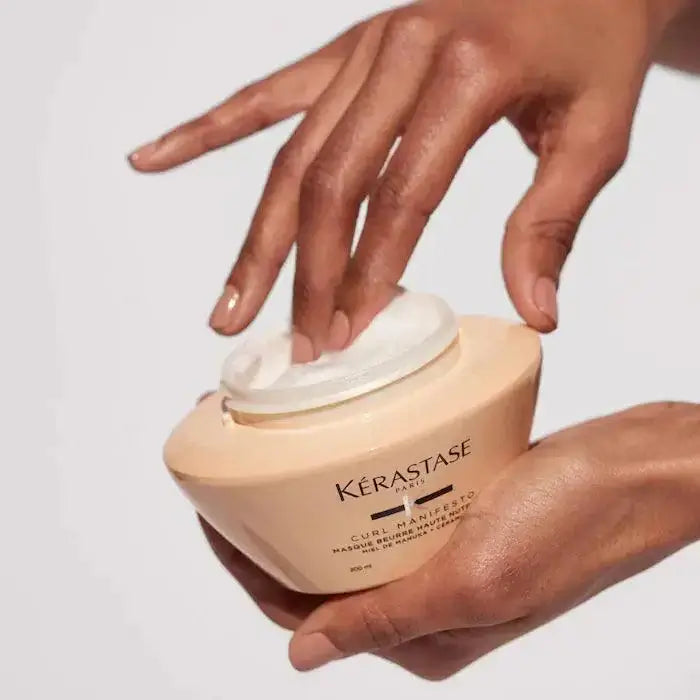 Person applying Curl Manifesto Masque Beurre Haute Nutrition for curly hair nourishment and hydration.