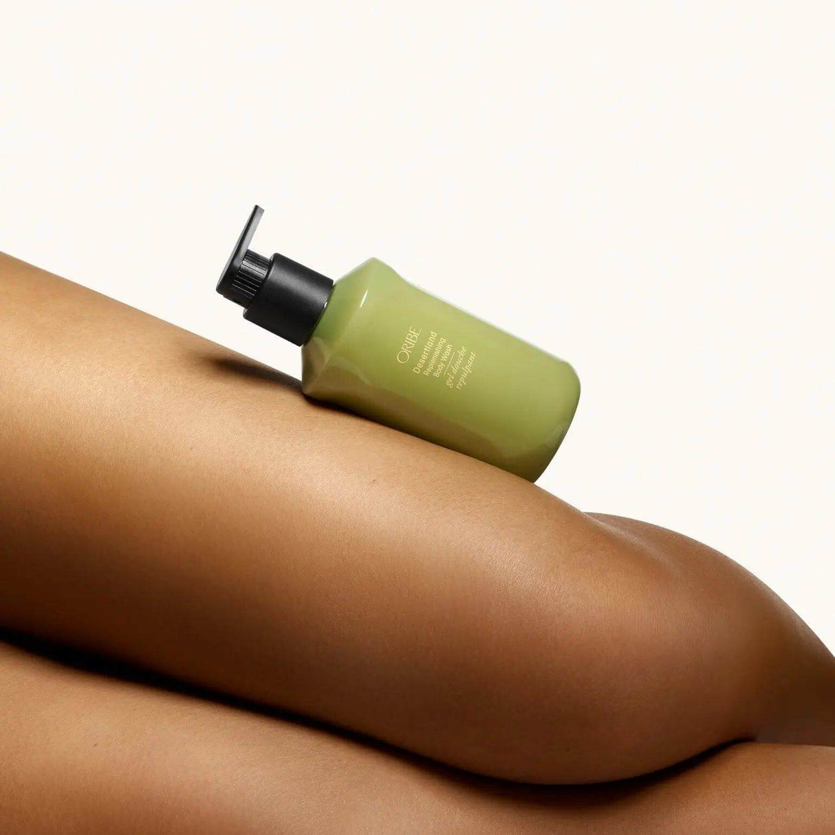 Alt Tag: Bottle of Oribe Desertland Replenishing Body Wash resting on smooth, moisturized skin, emphasizing hydration and luxury.