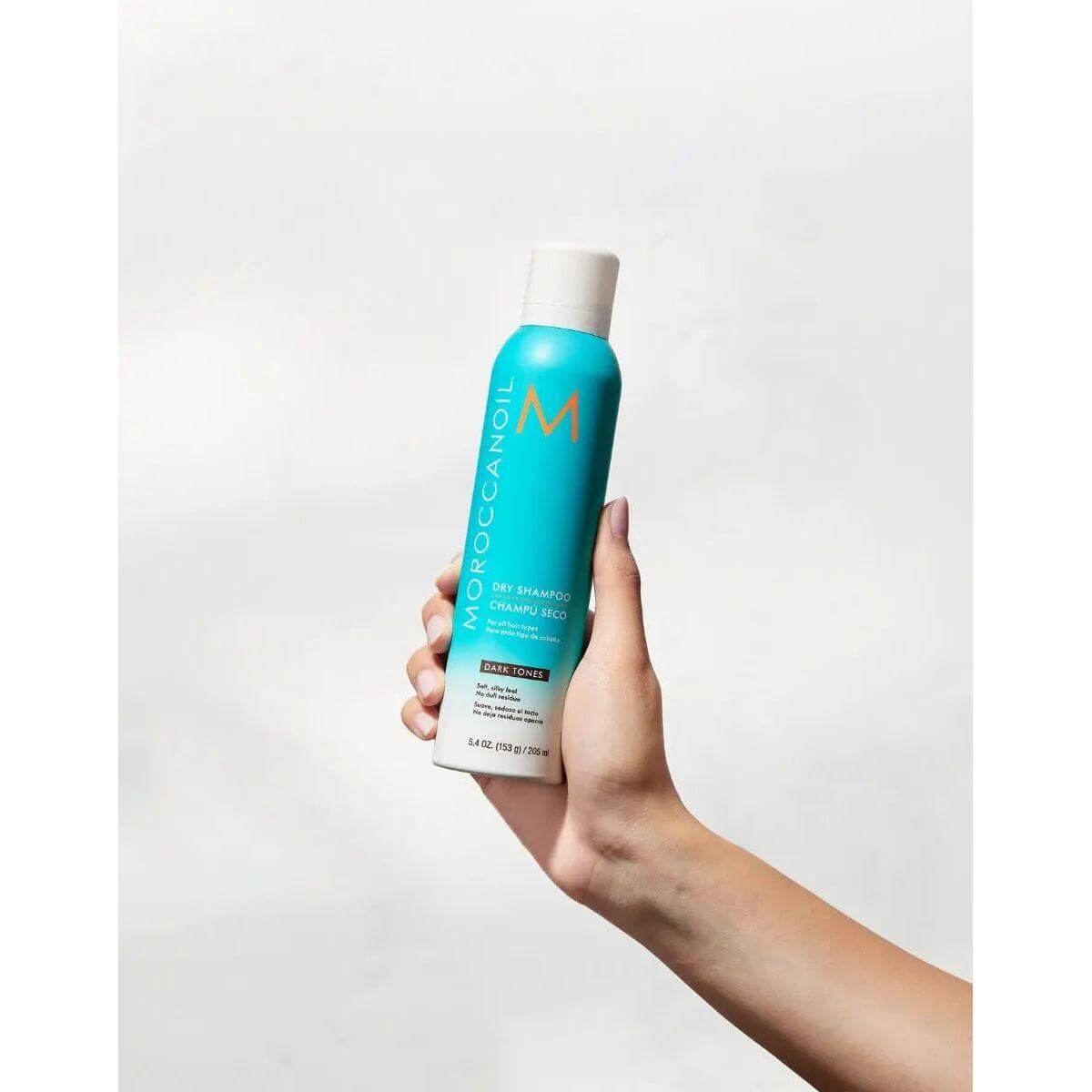 Moroccanoil Dry Shampoo for Dark Tones bottle held in hand, showcasing ultra-fine, oil-absorbing formula for dark hair.