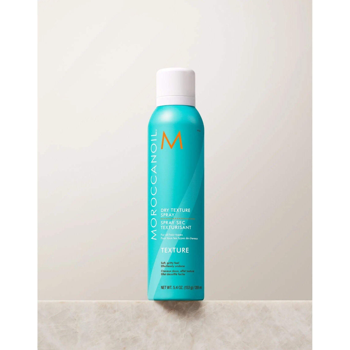 Moroccanoil Dry Texture Spray with argan oil for creating textured volume and long-lasting hold, shown in turquoise bottle.