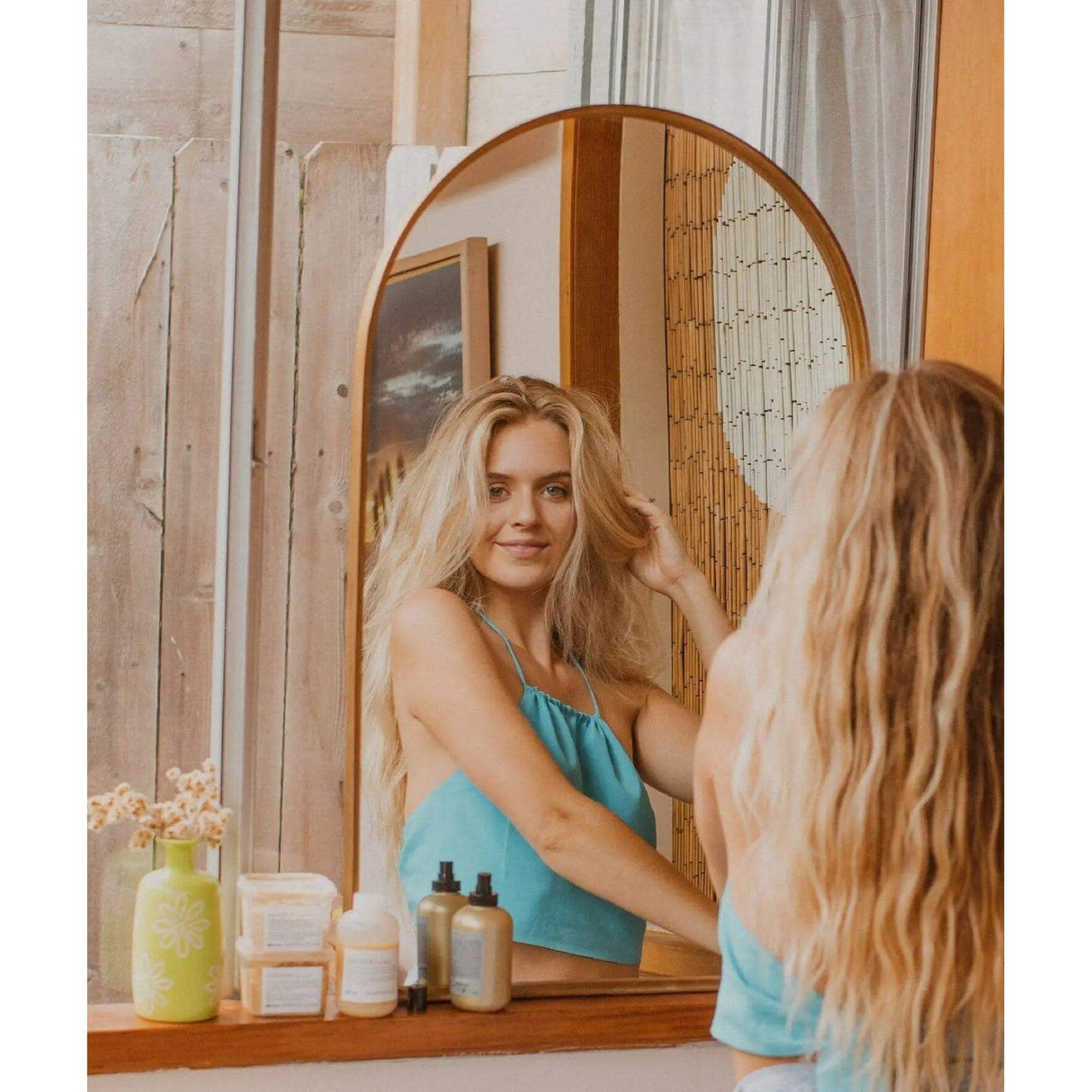 Woman with beach waves using Davines Easy Beach Waves Set including shampoo, conditioner, hair mask, and sea salt spray.