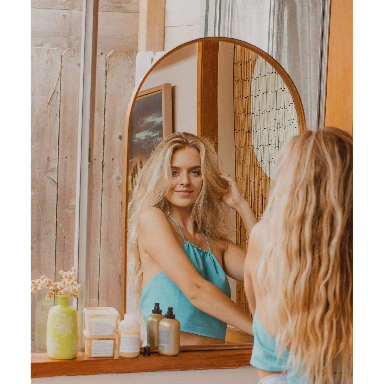 Woman with beach waves using Davines Easy Beach Waves Set including shampoo, conditioner, hair mask, and sea salt spray.