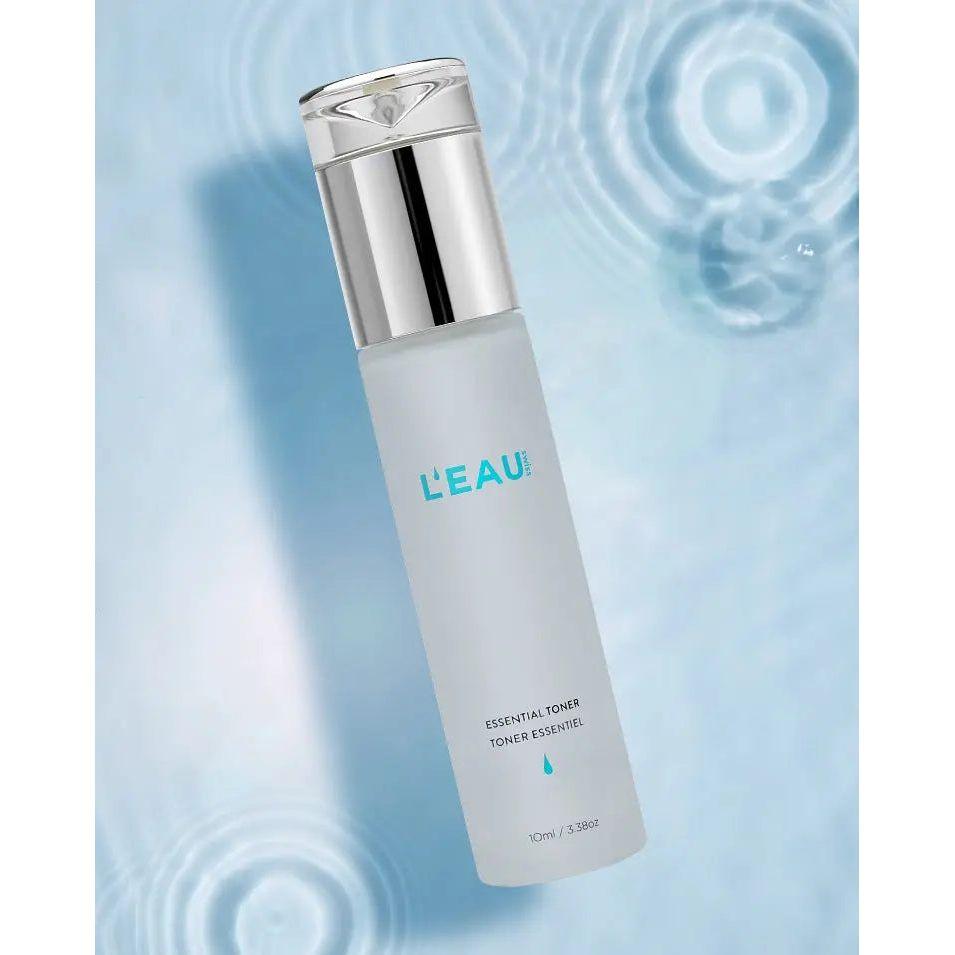 Bottle of Essential Toner with calming Snow Algae extract for firm, tight skin, displayed on a blue water ripple background.