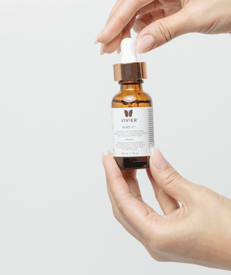 Vivier Kine-C antioxidant serum bottle being held, featuring 10% Vitamin C for reducing fine lines and enhancing skin hydration.