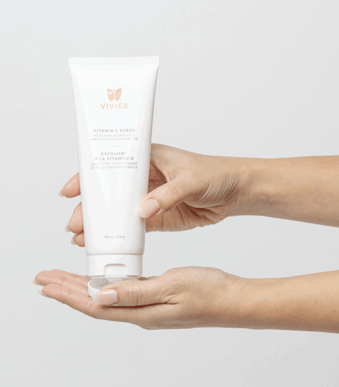 Hands holding Vivier Vitamin C Scrub, a facial and body exfoliant with Vitamin C and Hyaluronic Acid for radiant, smooth skin.