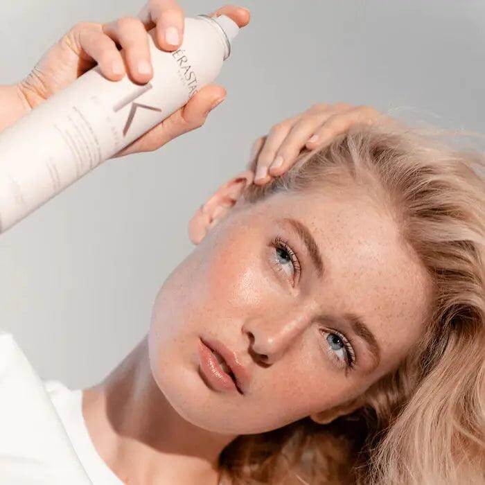 Woman using Kérastase Fresh Affair Oil-Absorbing Dry Shampoo for revitalized hair without residue.