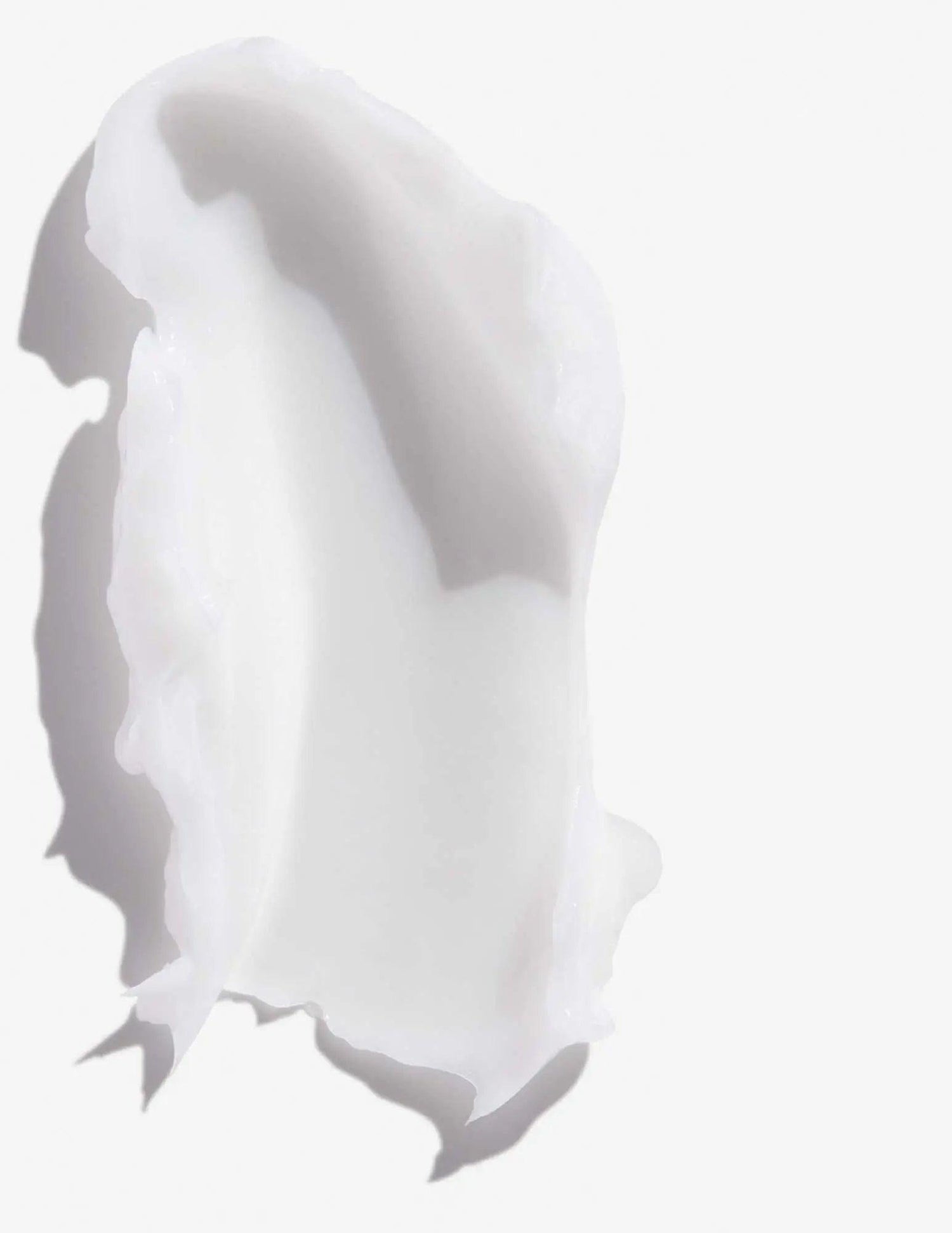 Scoop of Redken Frizz Dismiss Conditioner showcasing creamy texture designed to reduce frizz and smooth all hair types.