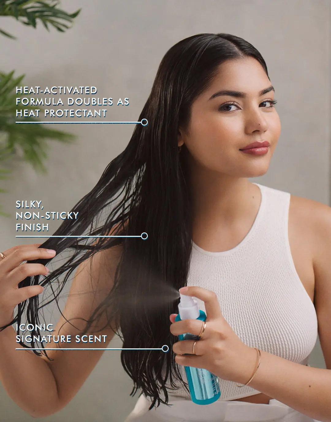 Woman applying Frizz Shield Spray for glossy, frizz-free hair with heat protection and a non-sticky finish.