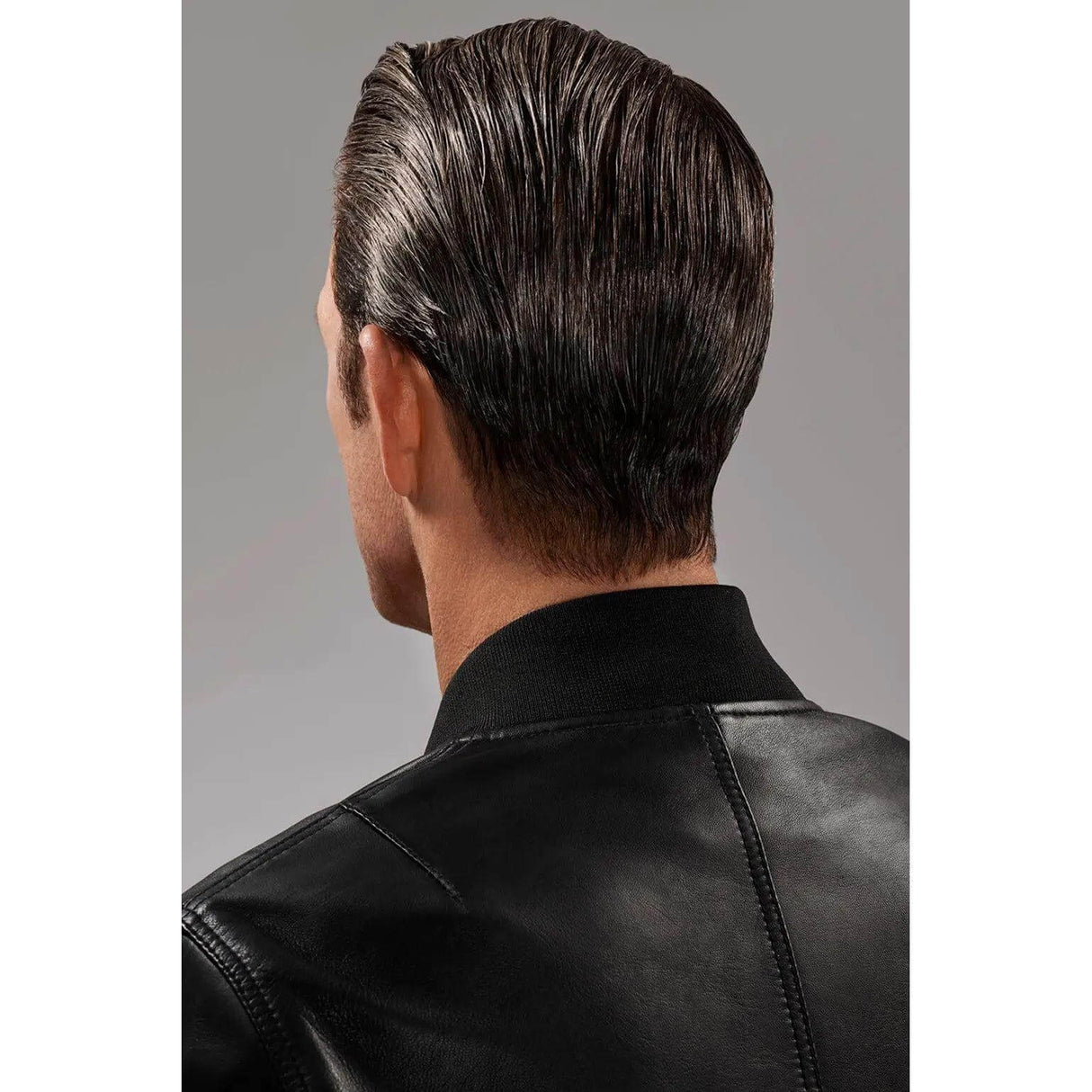 Man with sleek, shiny hair styled using gel serum, wearing a black leather jacket, showcasing the product's flexible hold and glossy finish.
