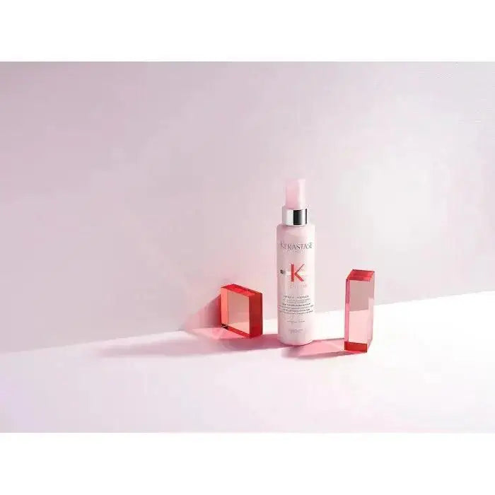Kérastase Genesis Défense Thermique thermal protectant spray positioned stylishly with red geometric shapes, designed for hair protection.