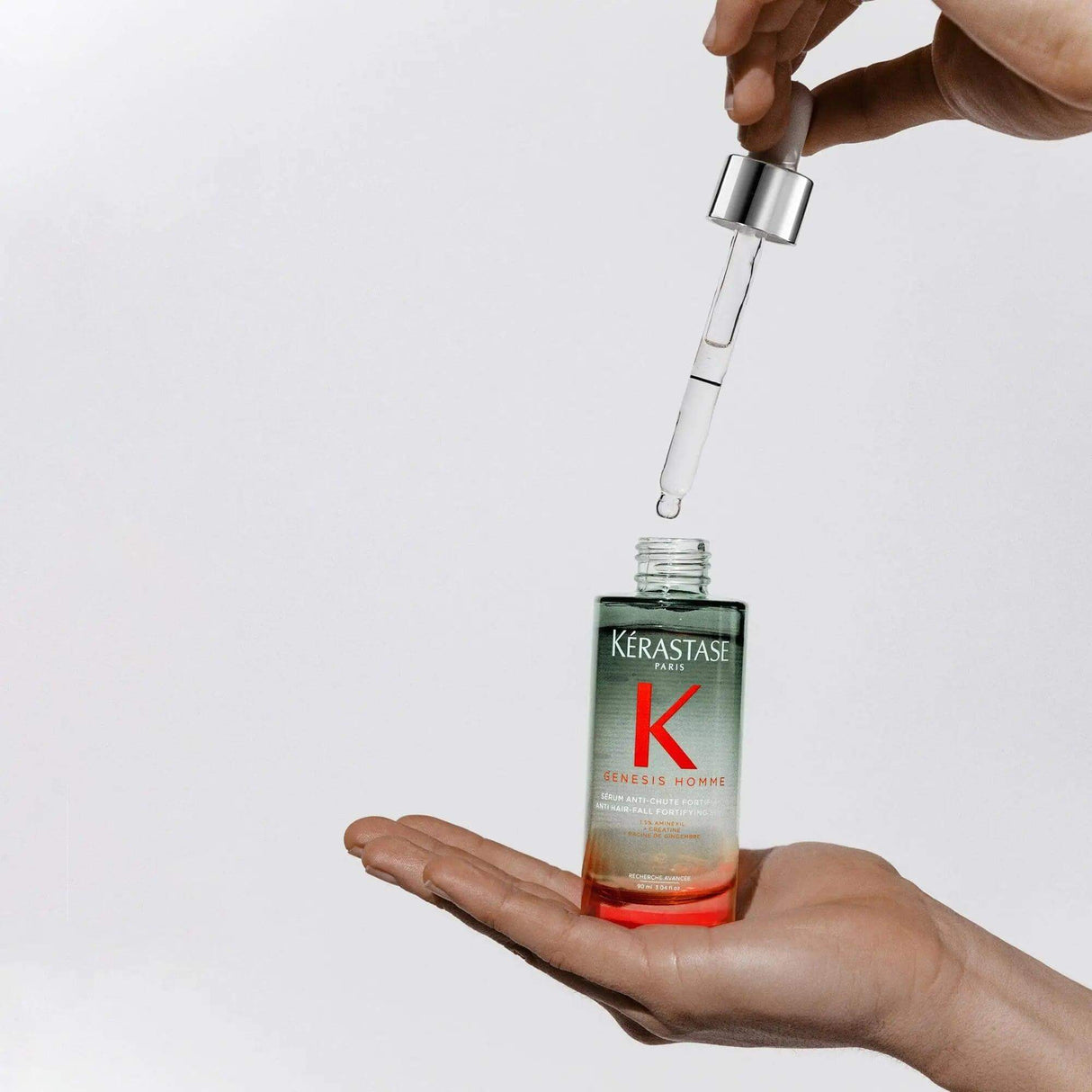 Kérastase Genesis Homme hair serum for men, fortifying anti-hair loss treatment in a bottle with dropper, held in hand