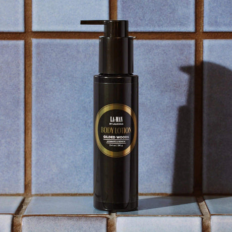 Luxurious Gilded Woods Body Lotion bottle on tiled surface, featuring nourishing ingredients like Shea Butter, Aloe Vera, and Vitamins.