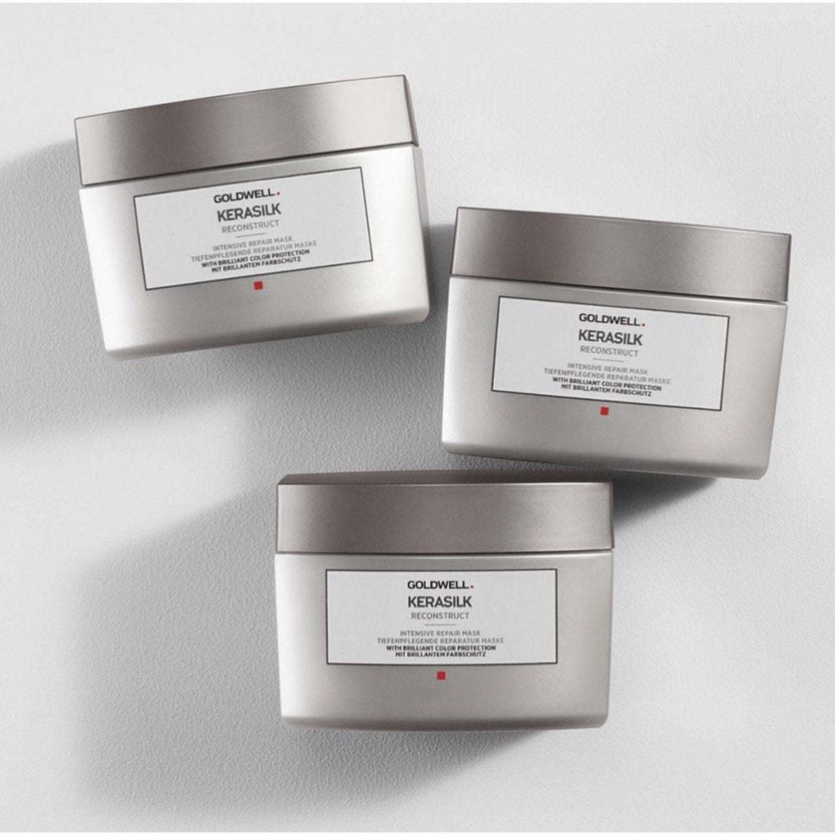 Three jars of Goldwell Kerasilk Reconstruct Intensive Repair Mask for dry and damaged hair, providing hydration and protection.