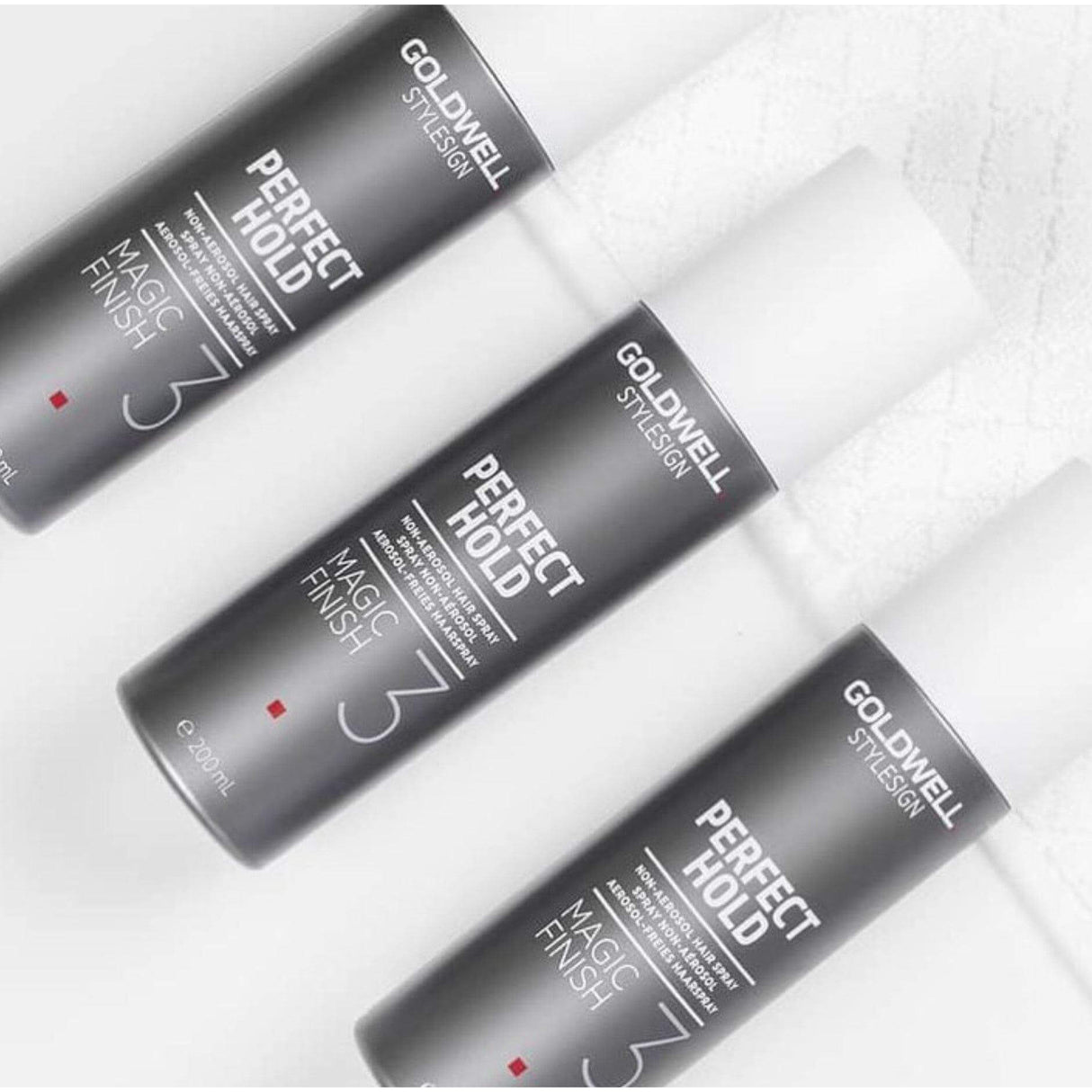 Goldwell Perfect Hold Magic Finish Hairspray bottles on a white surface, offering light to medium hold with enhanced shine and humidity protection.