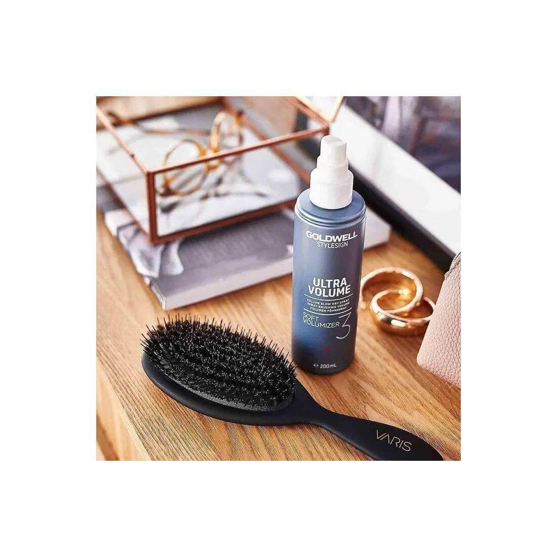 Goldwell Stylesign Ultra Volume Soft Volumizer Blow-Dry Spray with hairbrush on wooden vanity.
