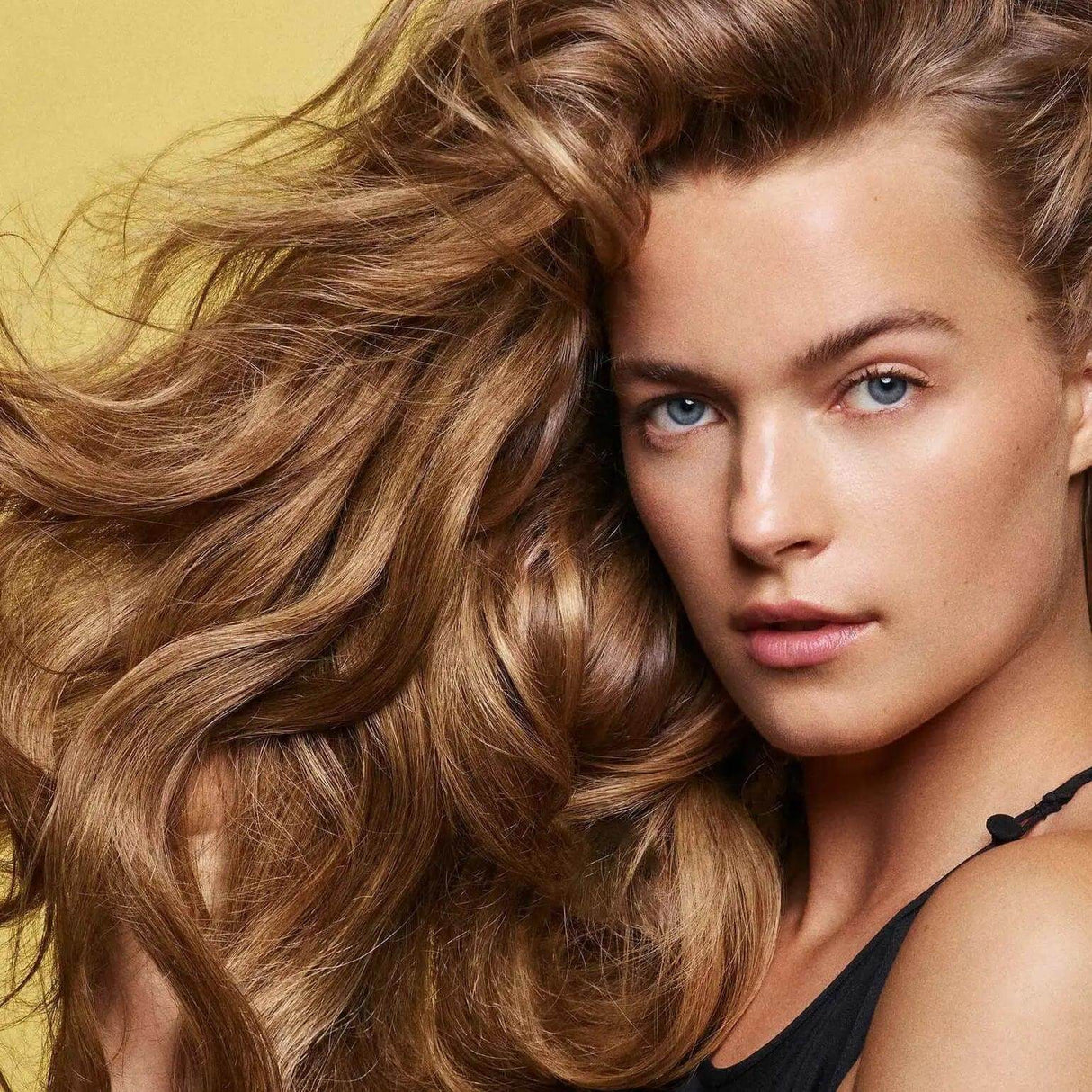 Woman with voluminous hair showcasing the effects of Hair Alchemy Resilience Shampoo, highlighting strength and shine.