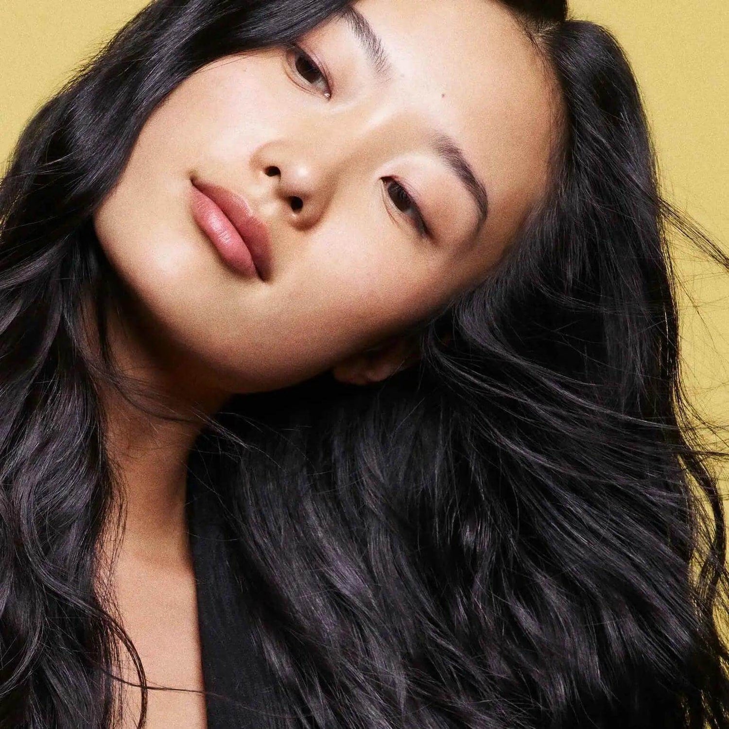Woman with lustrous black hair showcasing the effects of Hair Alchemy Resilience Shampoo.