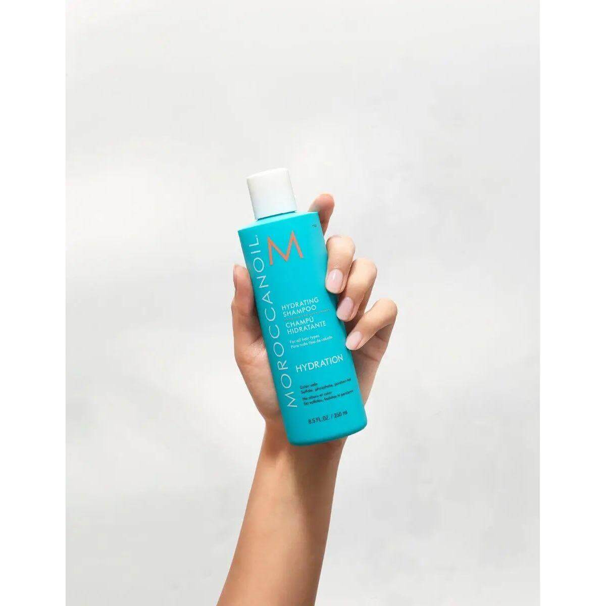 Hand holding Moroccanoil Hydrating Shampoo bottle for nourishing hair care.