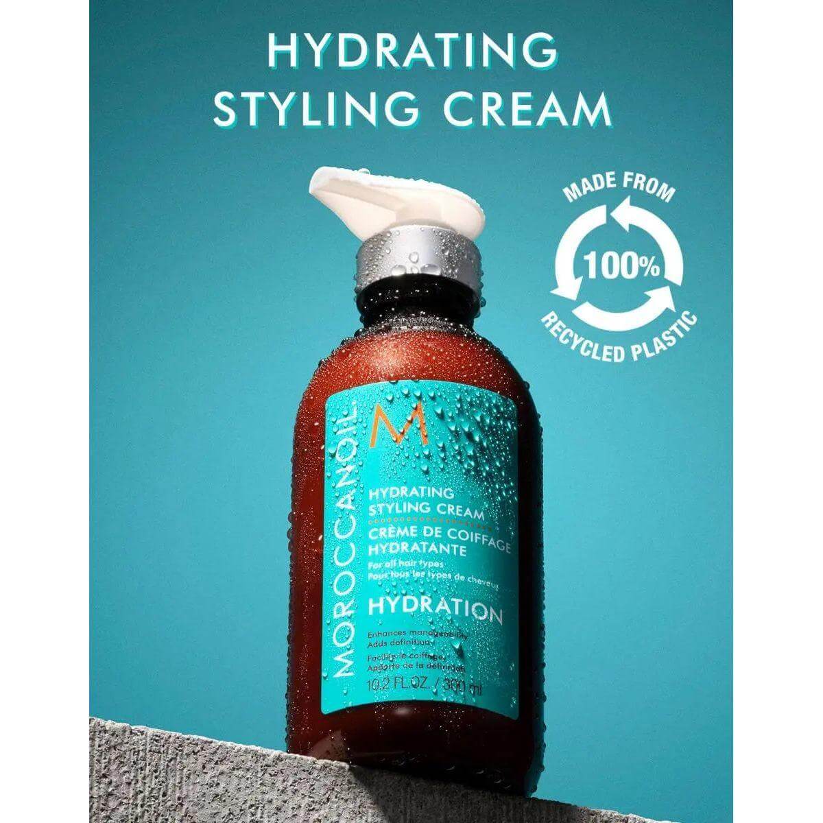 Moroccanoil Hydrating Styling Cream bottle with 100% recycled plastic packaging against a turquoise background.