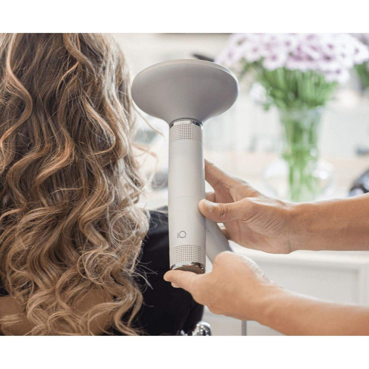 Styling hair with the ergonomic IQ Perfetto Hair Dryer and diffuser attachment in a salon setting.