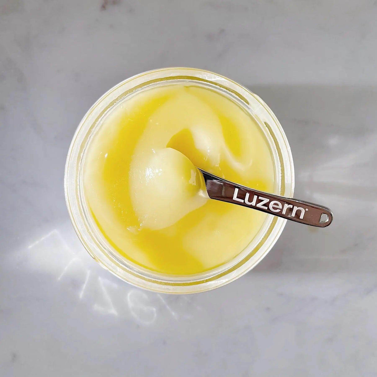 Top view of L'Essentials Emulsion 6 with spoon, showcasing its rich, nutritious blend of oils in a luxurious balm texture.
