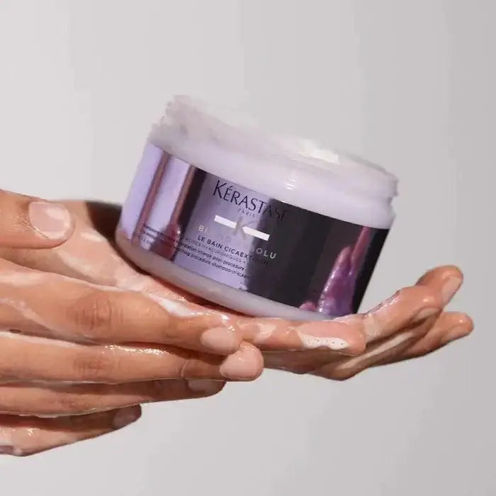 Person holding Kerastase Le Bain Cicaextreme, restorative shampoo for extremely dry, damaged hair, providing deep hydration.