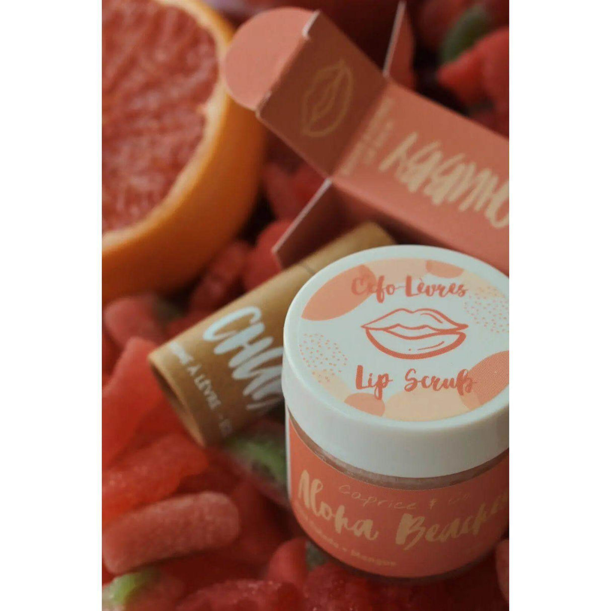 Aloha Beaches Lip Scrub jar with tropical pineapple and mango flavor, featuring exfoliating sugar, jojoba oil, and shea butter in pink container.