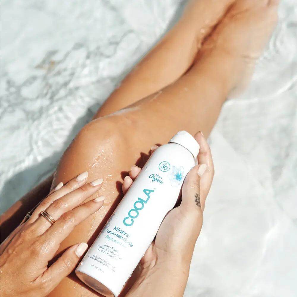 Applying Mineral Body Organic Sunscreen Spray SPF 30 by the pool, featuring a matte, fragrance-free formula with zinc oxide protection.