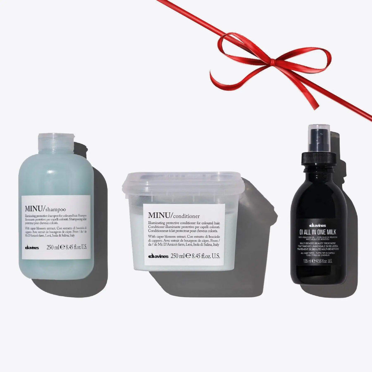 Minu + Oi Set with shampoo, conditioner, and all-in-one milk for vibrant color and shine, with a decorative red ribbon.