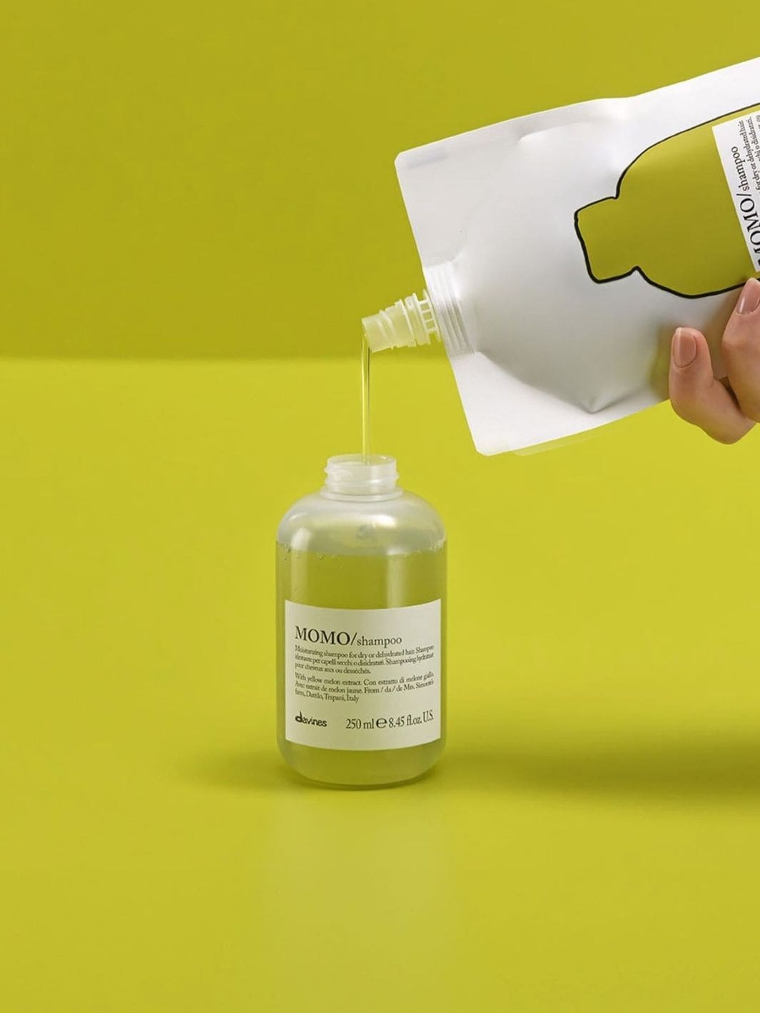 Momo Shampoo Refill pouring into bottle, enriched with yellow melon for deep hydration, ideal for dry hair, providing softness and shine.