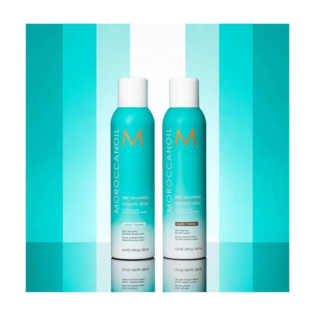 Moroccanoil Dry Shampoo Light Tones bottles against a blue gradient background.