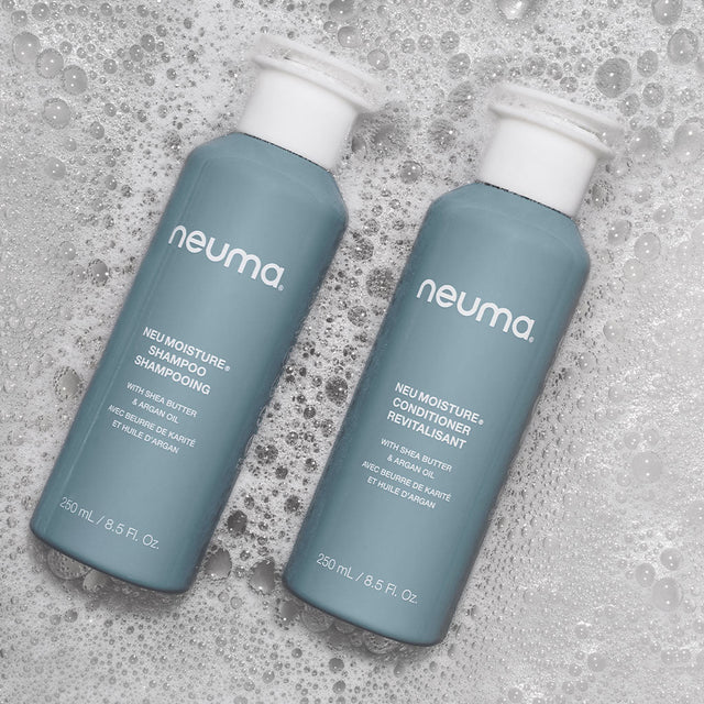 Neu Moisture Duo shampoo and conditioner bottles on a soapy background, providing hydration and shine for daily hair care.
