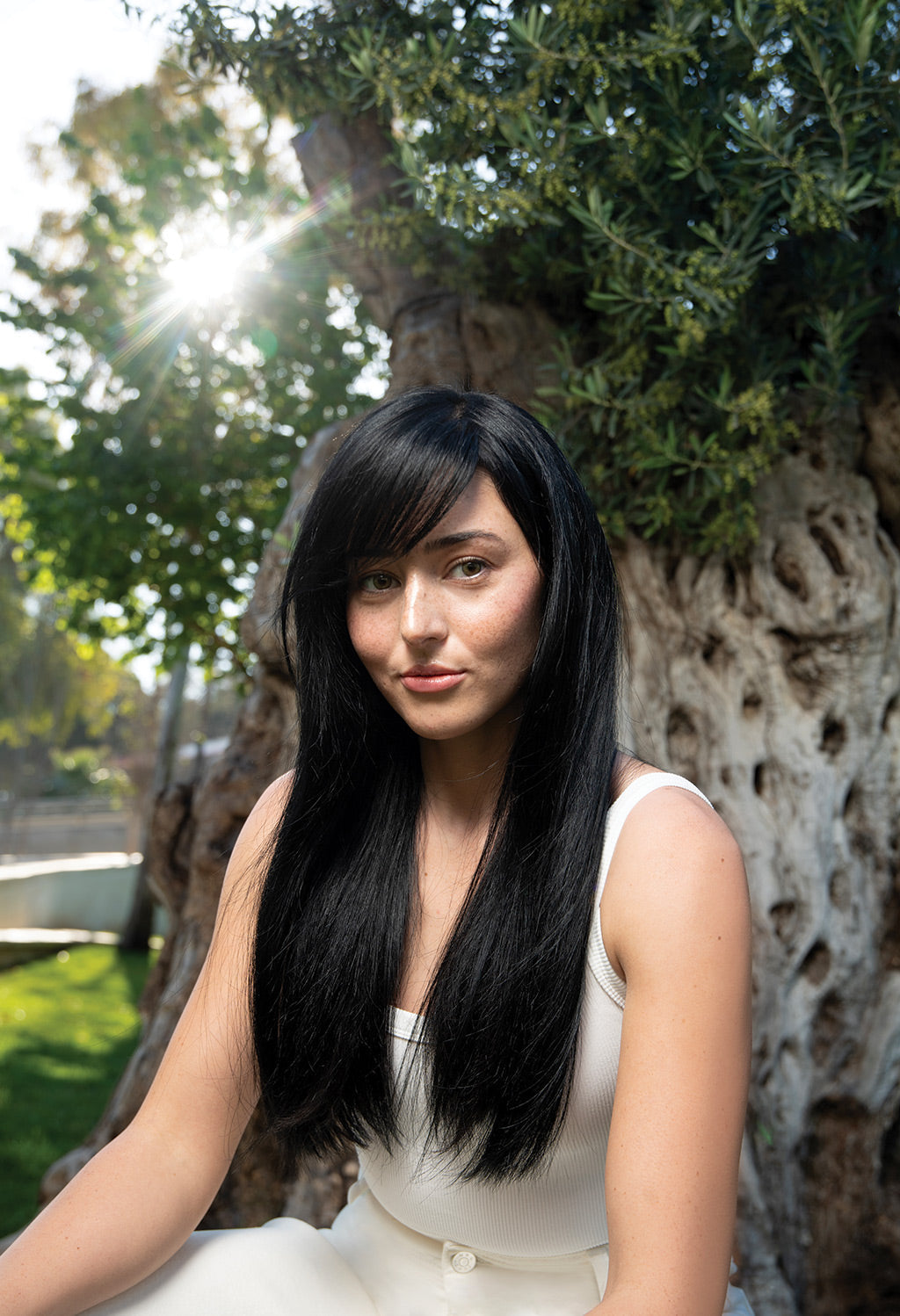 Woman with long, healthy black hair in nature, showcasing the results of Neu Repair Conditioner.