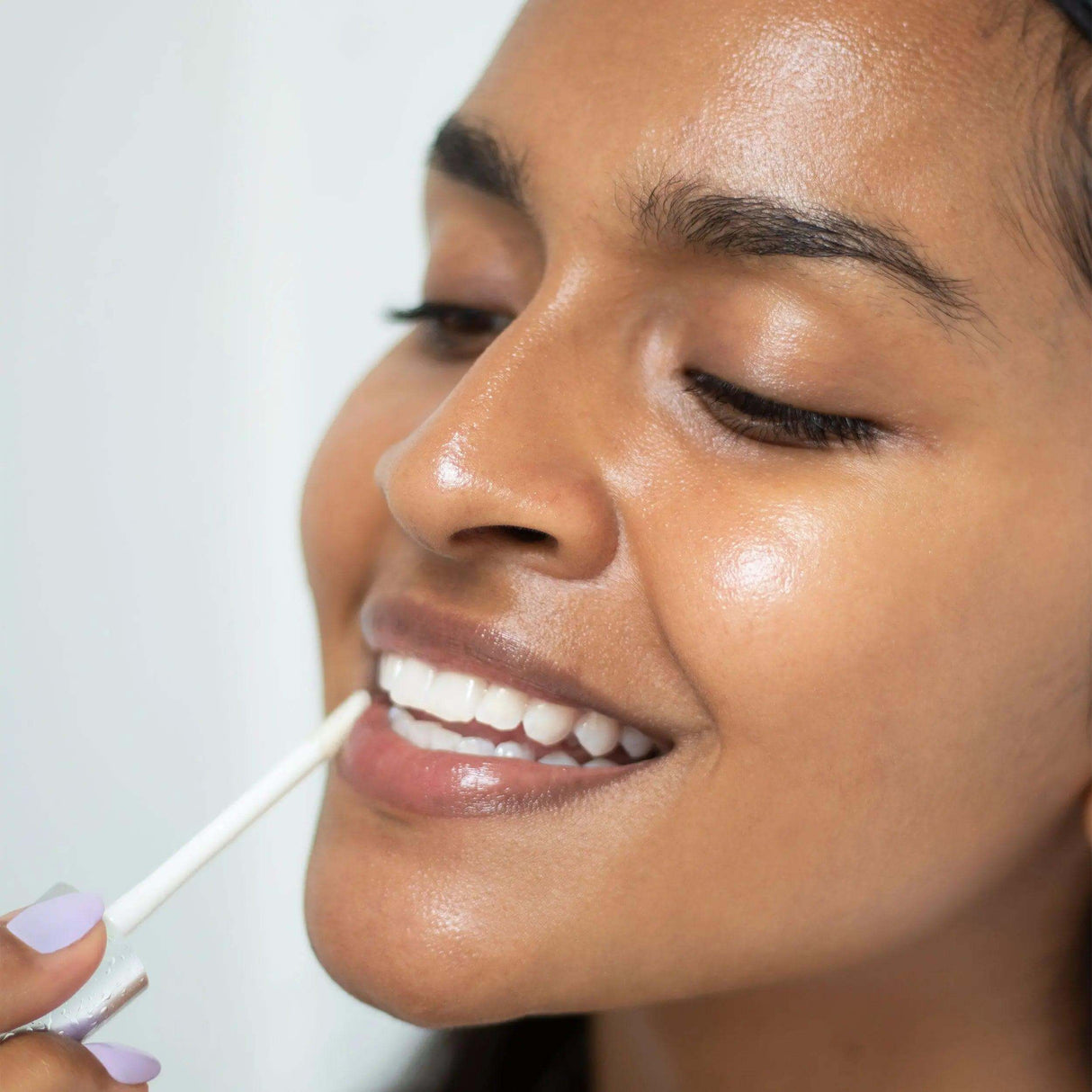Woman applying Night Lip Serum to lips, featuring plant extracts and vitamins for hydration and anti-aging benefits, 10g.