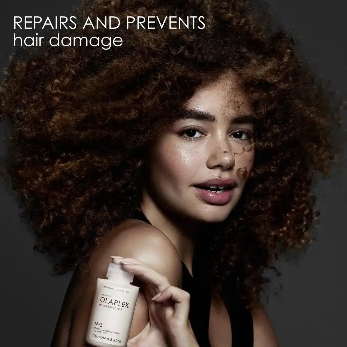 Woman holding Olaplex No.3 Hair Perfector, designed to repair and strengthen damaged hair to restore shine and health.