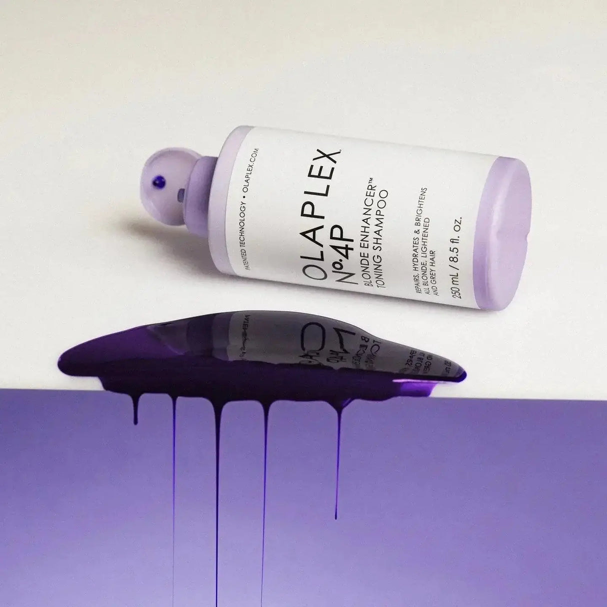 Olaplex Nº.4P Blonde Enhancer Toning Shampoo bottle with purple liquid spill enhancing blonde hair brilliance.