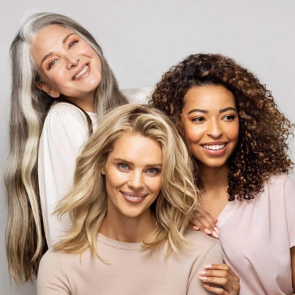 Three women with diverse hair types smiling, showcasing healthy hair after using Olaplex No.8 Bond Intense Moisture Mask.