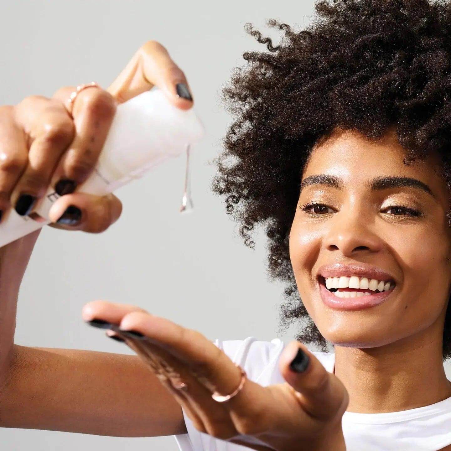 Woman applying Olaplex Nº.9 Bond Protector Nourishing Hair Serum for strong, nourished hair against damage and frizz.