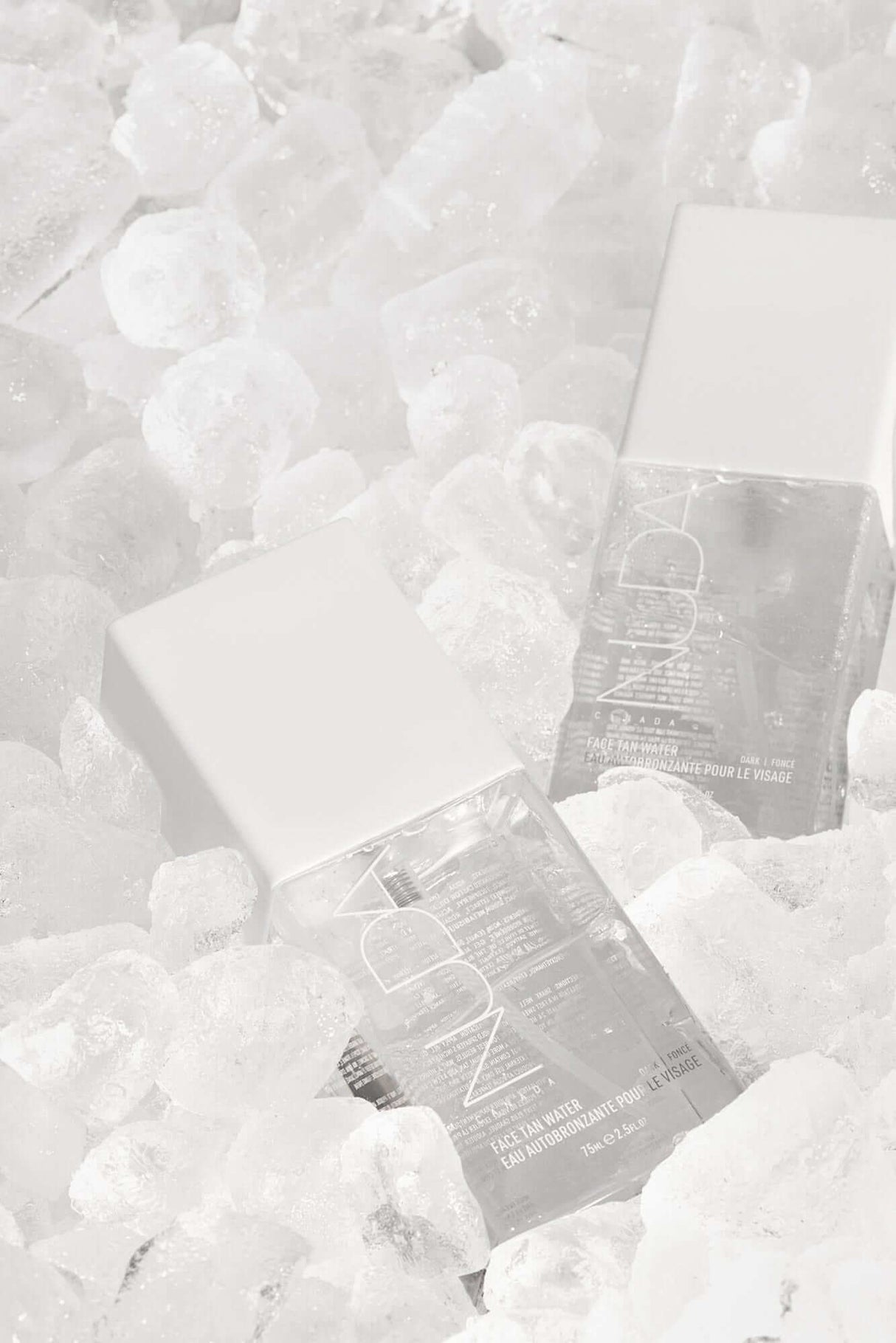Skincare products partially submerged in ice cubes, showcasing cooling and refreshing qualities.